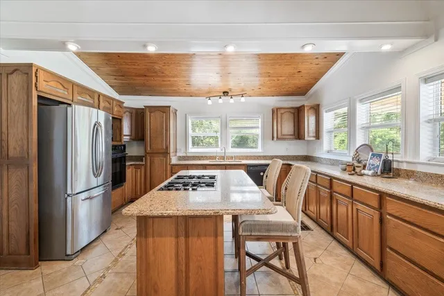 a kitchen with stainless steel appliances granite countertop a refrigerator a sink dishwasher and a stove with wooden cabinets