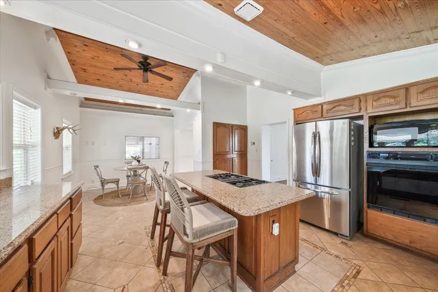 a open kitchen with stainless steel appliances granite countertop table chairs and a refrigerator
