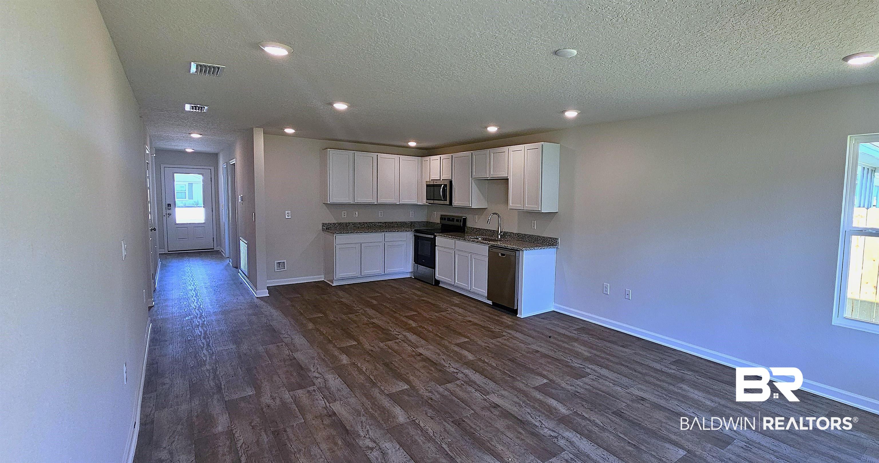 1148 Sweet Laurel Street Foley, AL 36535 - Photo 6 of 18 Kitchen featuring dark wood-type flooring, sink, white cabinets, appliances with stainless steel finishes, and a textured ceiling