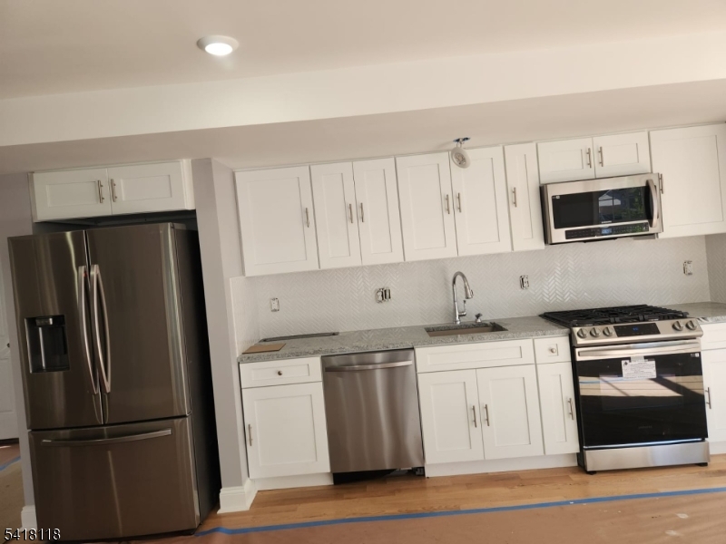 464 Walnut Street Elizabeth, NJ 07201 - Photo 11 of 22 a kitchen with stainless steel appliances granite countertop a refrigerator a stove a sink and white cabinets