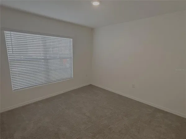 an empty room with windows and ceiling fan