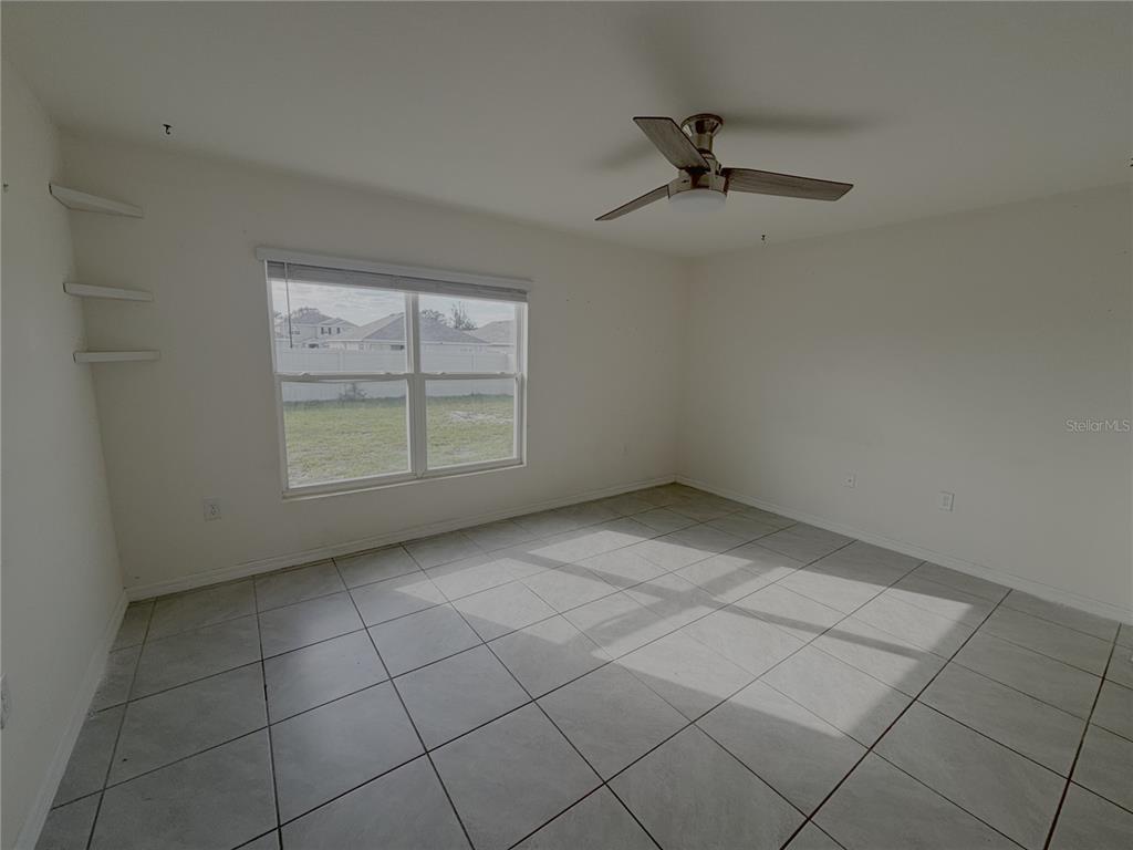 8940 Southwest 50th Terrace Ocala, FL 34476 - Photo 18 of 21 an empty room with windows and ceiling fan