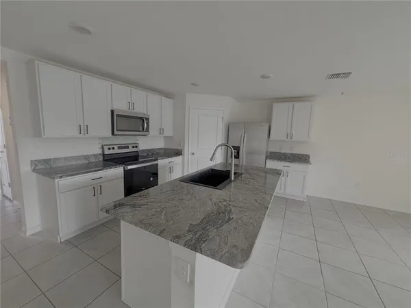 a kitchen with kitchen island sink refrigerator and cabinets