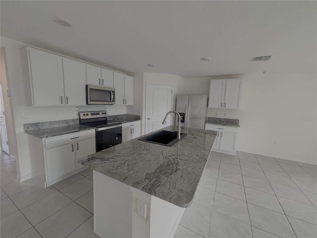 8940 Southwest 50th Terrace Ocala, FL 34476 - Photo 4 of 21 a kitchen with kitchen island sink refrigerator and cabinets