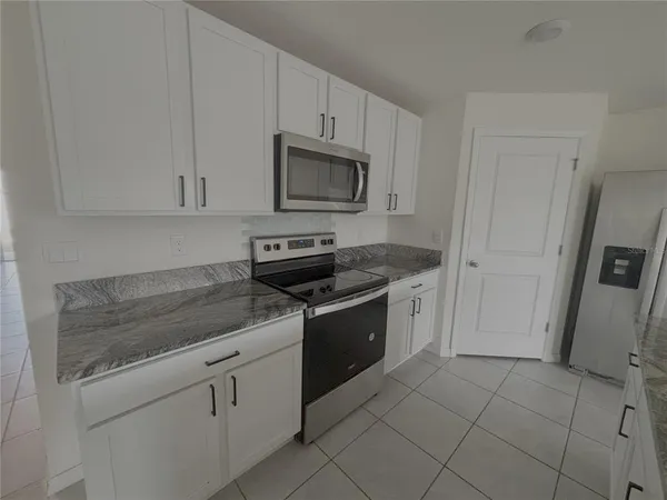 a kitchen with granite countertop white cabinets and stainless steel appliances