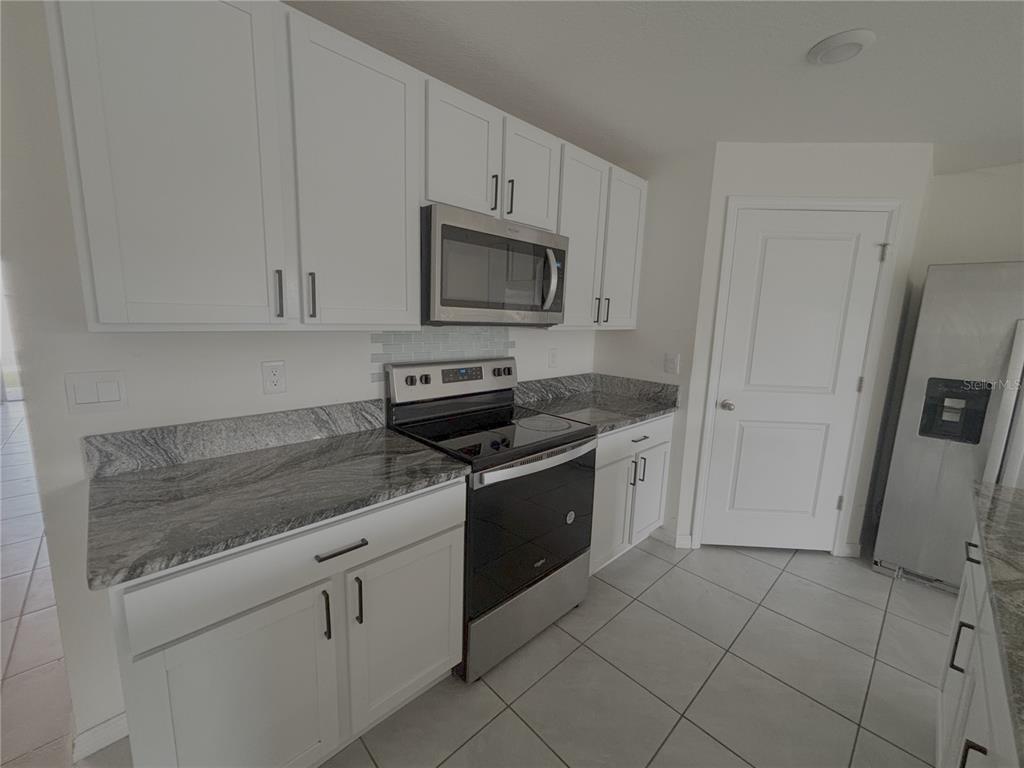 8940 Southwest 50th Terrace Ocala, FL 34476 - Photo 5 of 21 a kitchen with granite countertop white cabinets and stainless steel appliances