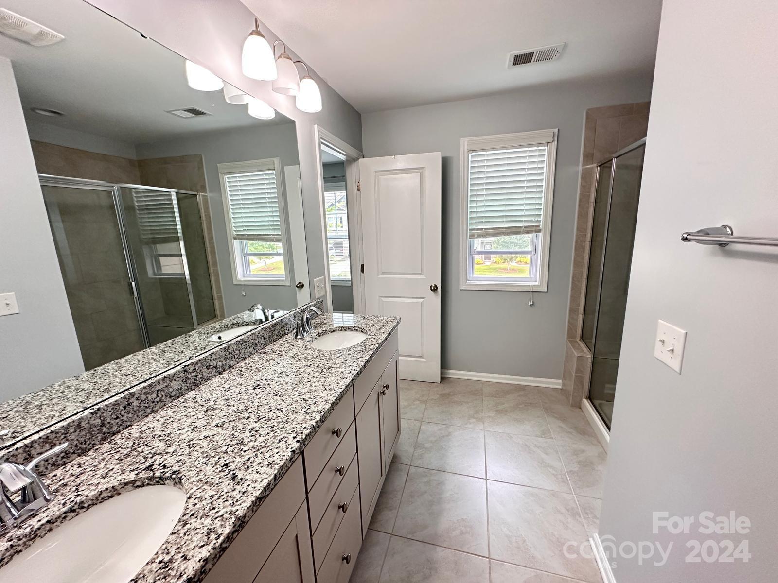 7040 Harris Bay Road Charlotte, NC 28269 - Photo 15 of 27 a bathroom with a granite countertop sink a mirror and a shower