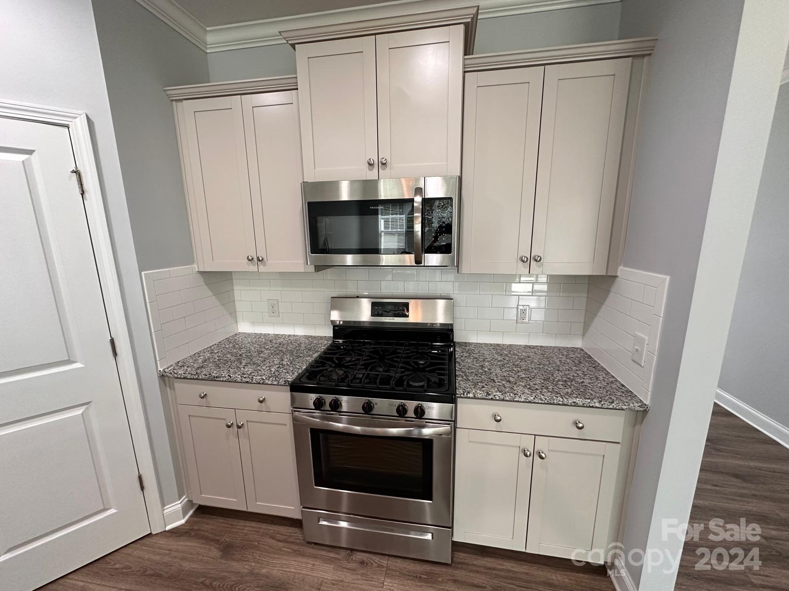 7040 Harris Bay Road Charlotte, NC 28269 - Photo 7 of 27 a kitchen with granite countertop white cabinets and black appliances