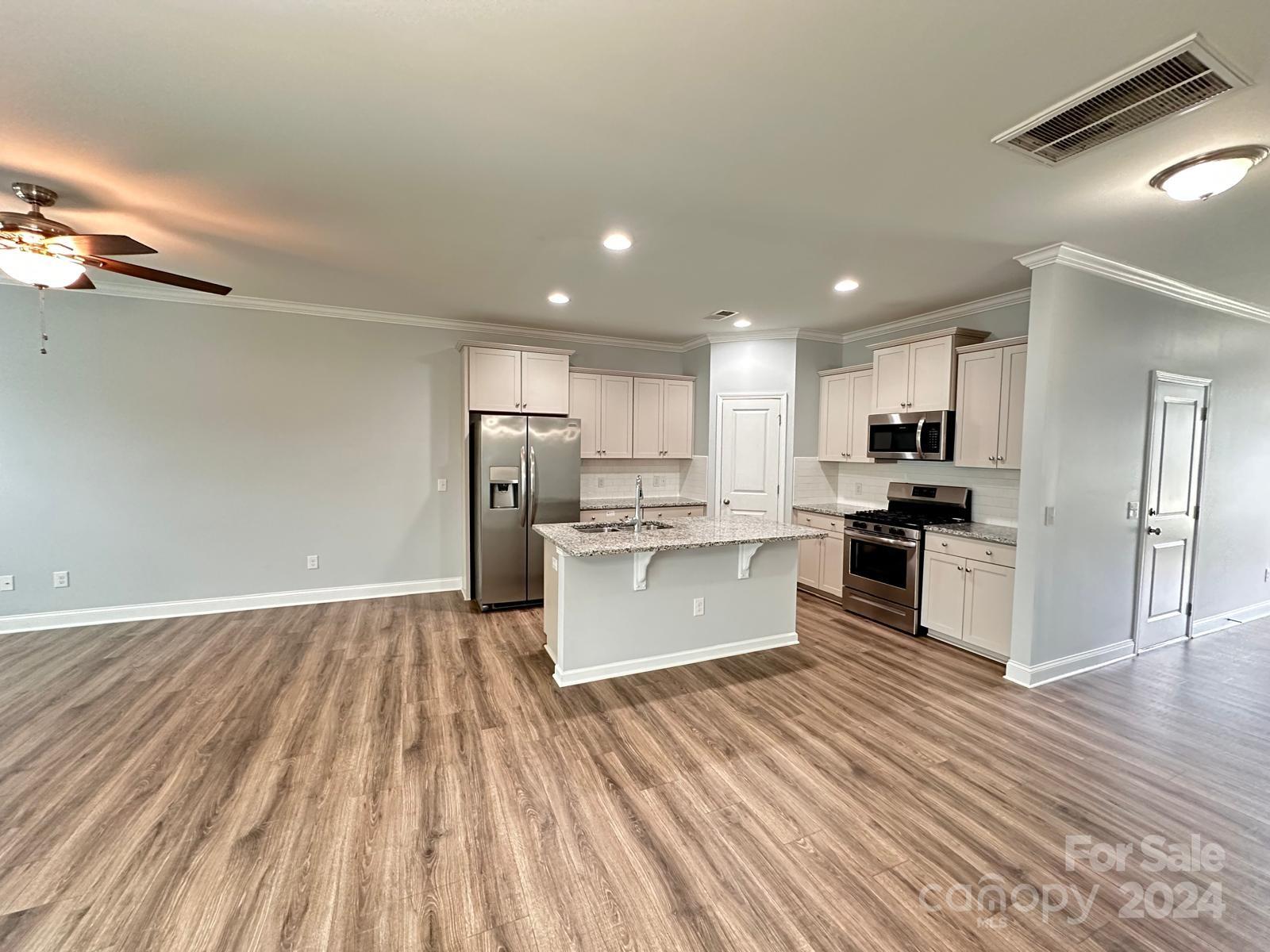 7040 Harris Bay Road Charlotte, NC 28269 - Photo 10 of 27 a large kitchen with kitchen island a sink dishwasher a refrigerator and wooden floor
