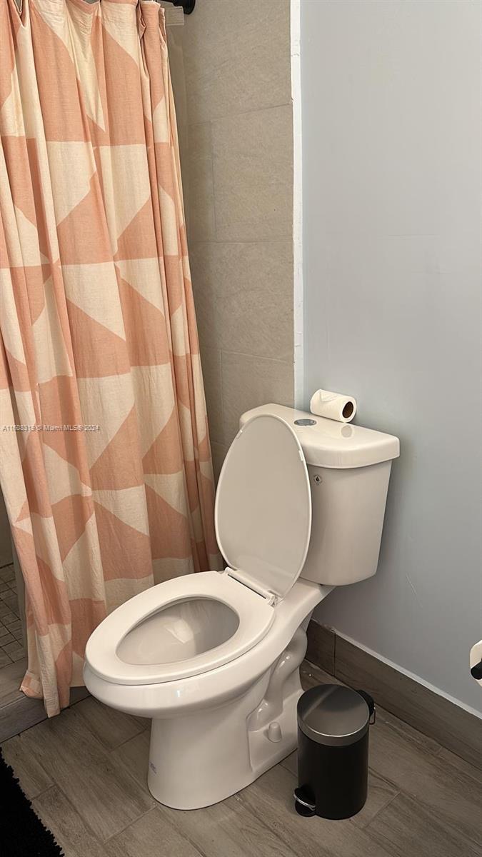 671 Northwest 50th Street, Unit 2 Miami, FL 33127 - Photo 9 of 14 a white toilet sitting next to a shower curtain