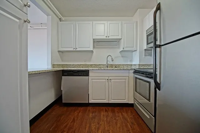 a kitchen with a sink cabinets stainless steel appliances and a window