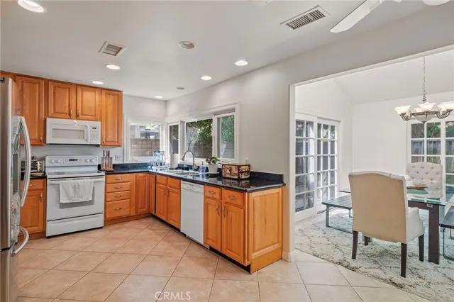 a kitchen with stainless steel appliances granite countertop a stove top oven a sink dishwasher a dining table and chairs with wooden floor