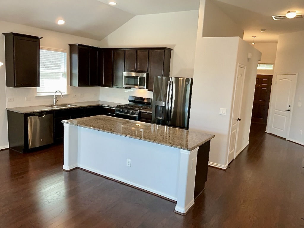 209 Penna Lane Georgetown, TX 78628 - Photo 4 of 19 a kitchen with stainless steel appliances a refrigerator a sink a stove a microwave and wooden floor