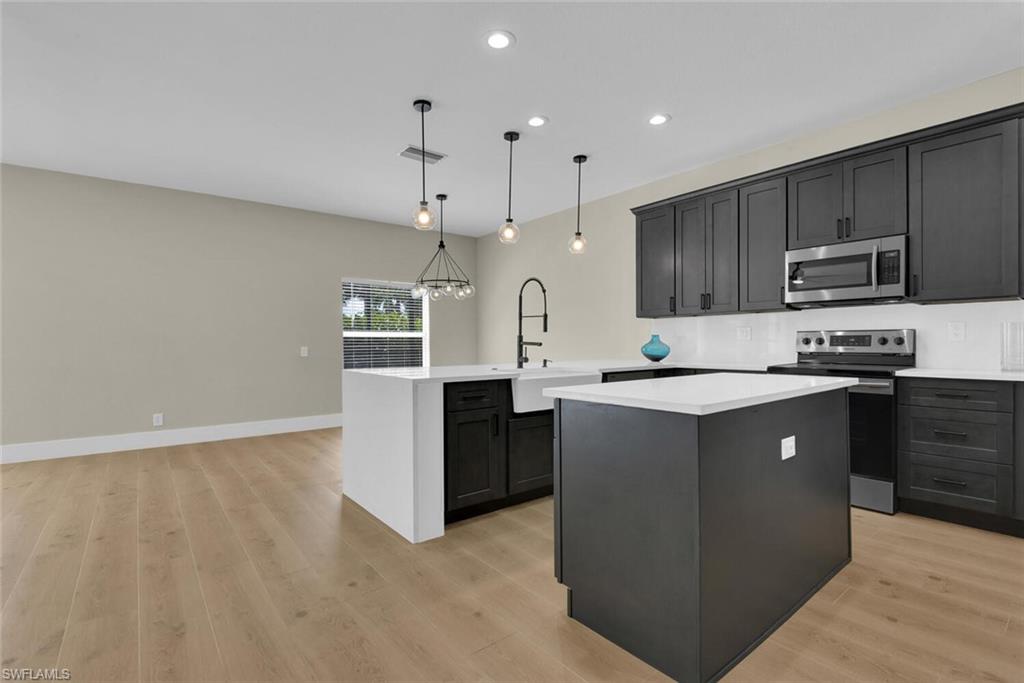 8883 Falcon Pointe Loop Fort Myers, FL 33912 - Photo 15 of 49 a large kitchen with stainless steel appliances kitchen island granite countertop a refrigerator a sink a stove and dishwasher with wooden floor