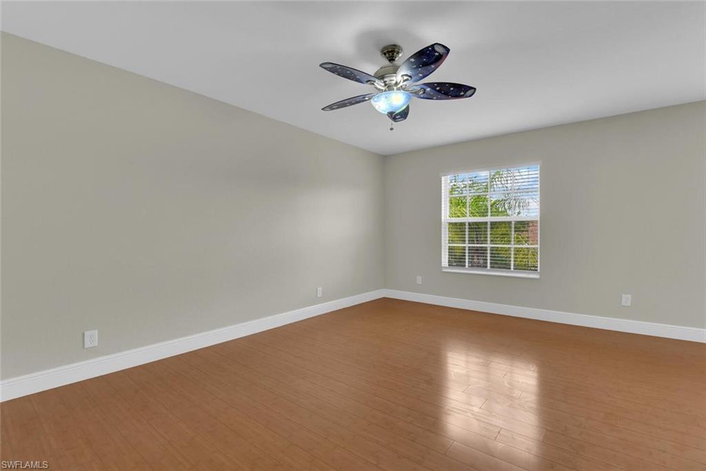 8883 Falcon Pointe Loop Fort Myers, FL 33912 - Photo 36 of 49 an empty room with wooden floor chandelier fan and windows