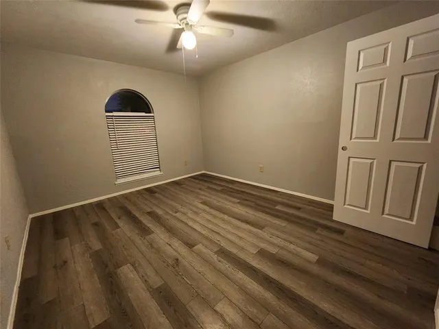 an empty room with wooden floor closet and fan