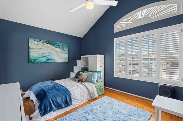 a bedroom with a bed a desk and chair with wooden floor