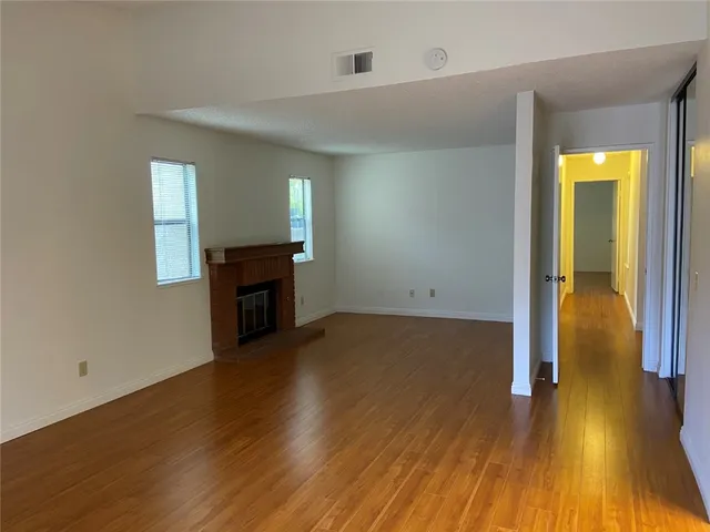 an empty room with wooden floor and a fireplace