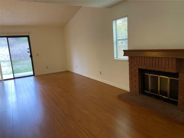 an empty room with wooden floor a fireplace and windows