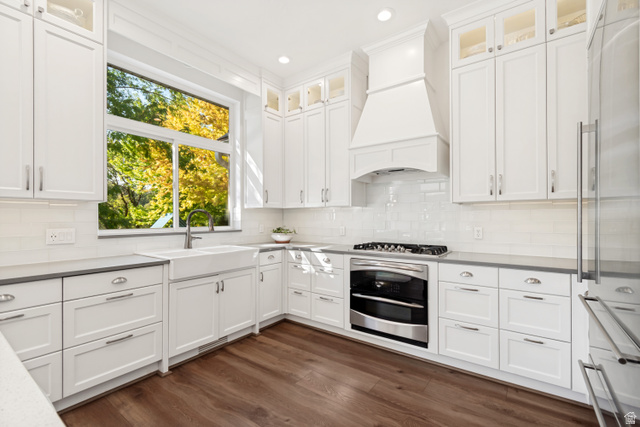 1567 Ridgeview Circle Farmington, UT 84025 - Photo 11 of 55 Chef's kitchen featuring white shaker cabinetry with stainless steel hardware, quartz countertops, a gas range with black stove and white hood, and stainless steel refrigerator