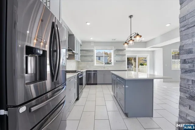 a large kitchen with stainless steel appliances kitchen island granite countertop a refrigerator and a sink
