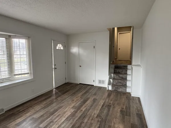 an empty room with wooden floor closet and windows