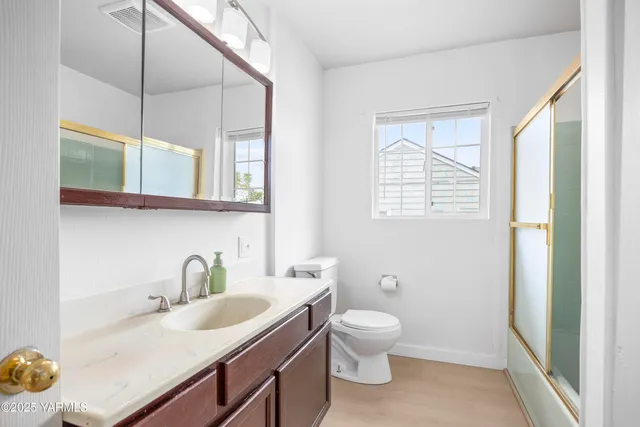 a bathroom with a granite countertop sink mirror vanity and toilet