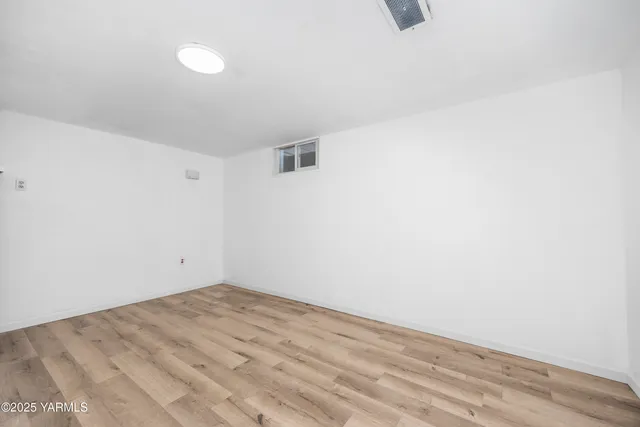 a view of empty room with wooden floor and fireplace