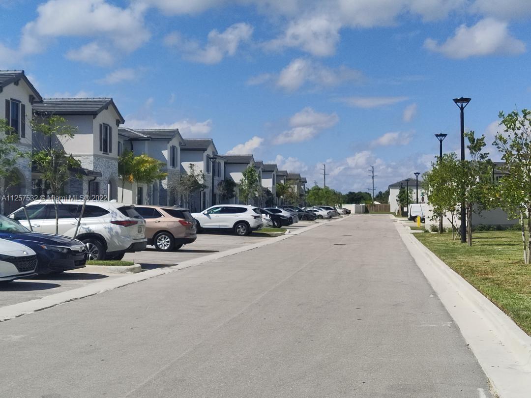 18232 Southwest 148th Road Miami, FL 33187 - Photo 31 of 32 a city street lined with cars parked in front of a house