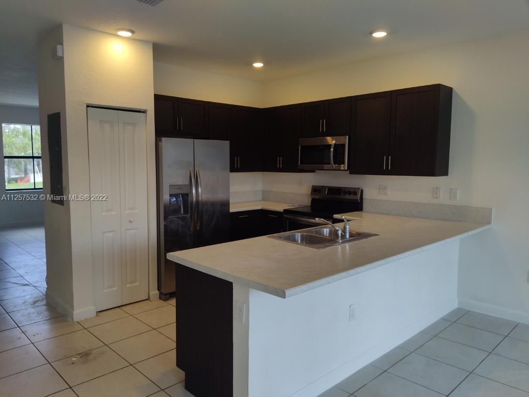 18232 Southwest 148th Road Miami, FL 33187 - Photo 4 of 32 a kitchen with kitchen island a sink stainless steel appliances and cabinets