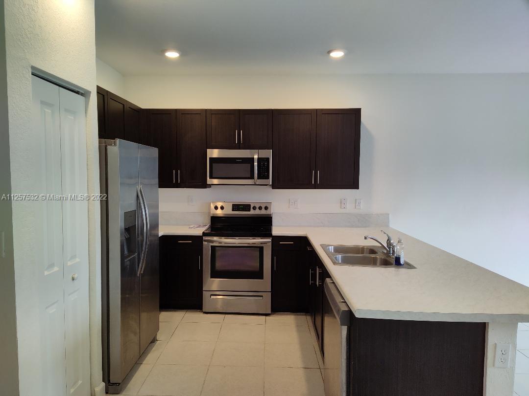 18232 Southwest 148th Road Miami, FL 33187 - Photo 5 of 32 a kitchen with stainless steel appliances a sink a stove a refrigerator a microwave a sink and cabinets