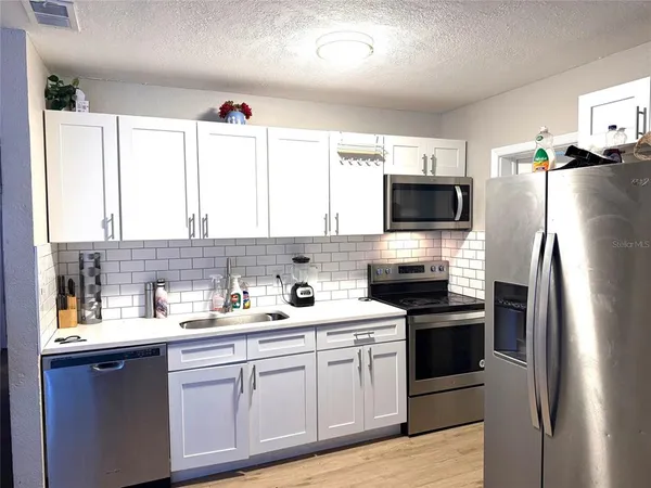 a kitchen with stainless steel appliances a stove sink microwave and refrigerator