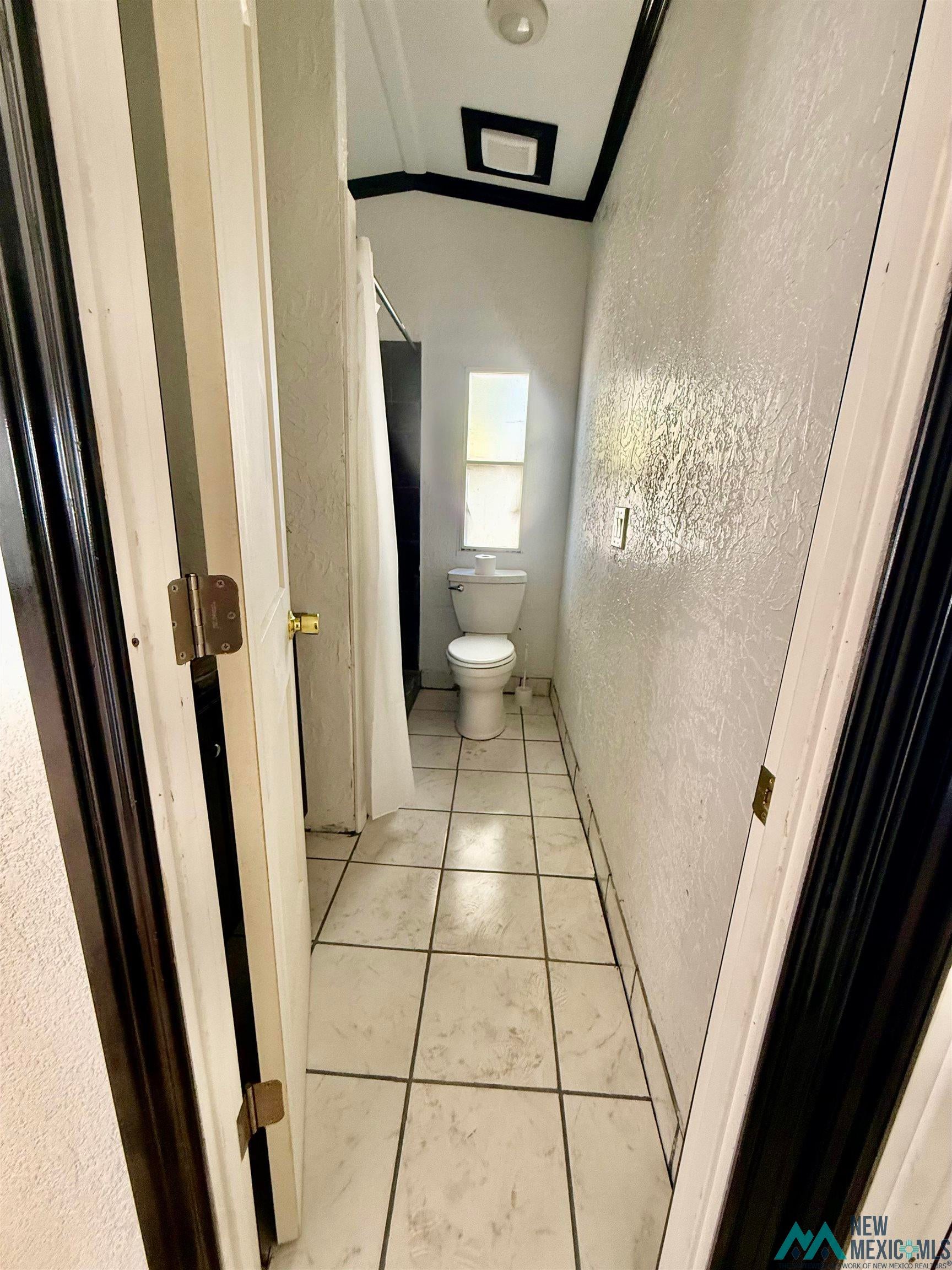 207 Chuckwagon Road Carlsbad, NM 88220 - Photo 10 of 19 Bathroom with a textured wall, ornamental molding, and light tile patterned flooring