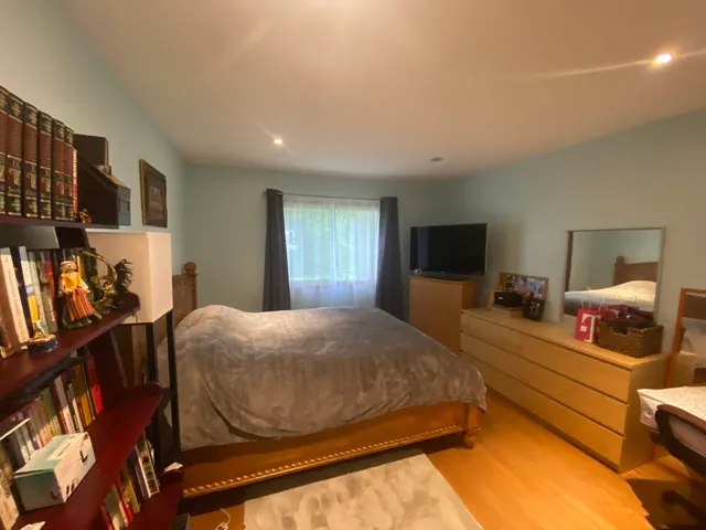 a bedroom with a bed and a flat tv screen on the dresser