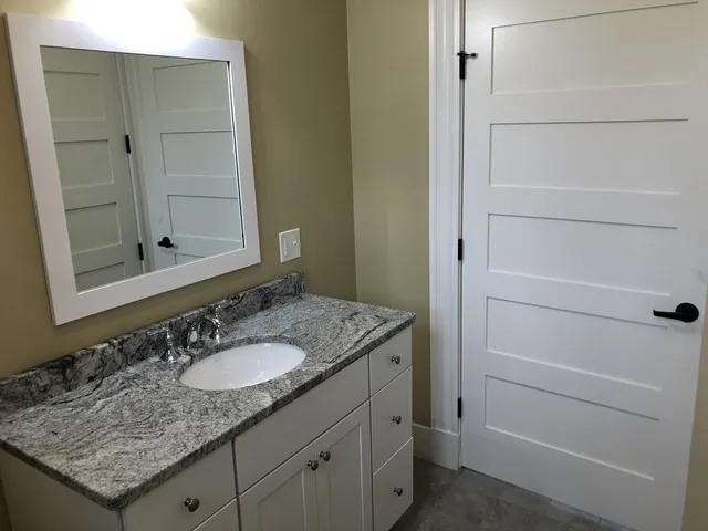 a bathroom with a granite countertop sink and a toilet