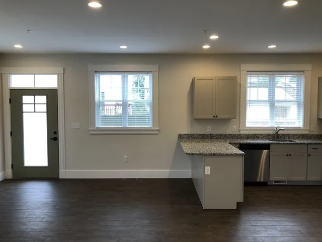 a kitchen with granite countertop white cabinets and wooden floor