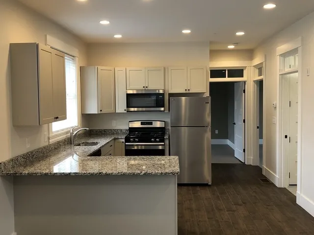 a kitchen with stainless steel appliances granite countertop a refrigerator a stove a sink and a microwave