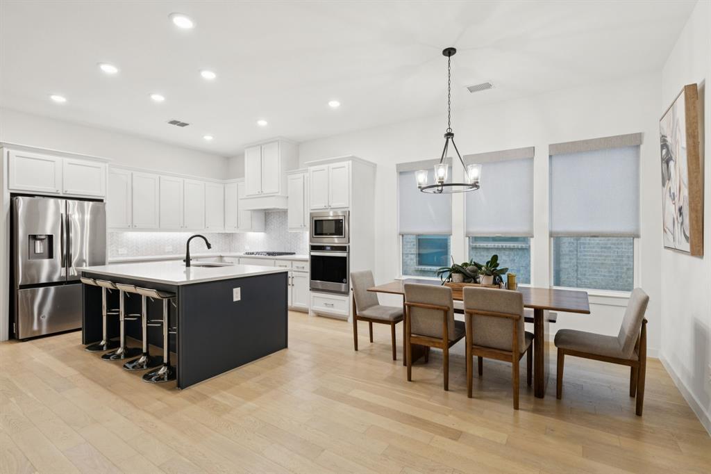 547 Embargo Drive Fate, TX 75189 - Photo 9 of 36 a kitchen with stainless steel appliances kitchen island granite countertop a sink dishwasher a refrigerator and a dining table with the chairs