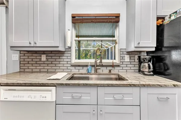 a kitchen with granite countertop stainless steel appliances white cabinets sink and a granite counter top