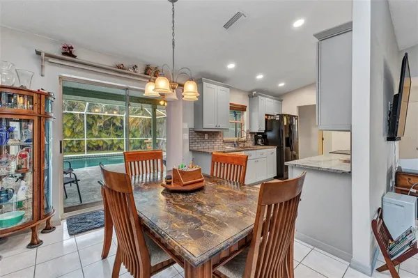 a dining room with stainless steel appliances granite countertop a table chairs and a view of kitchen