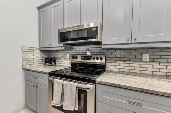 a kitchen with stainless steel appliances granite countertop white cabinets and a stove a oven with white countertops