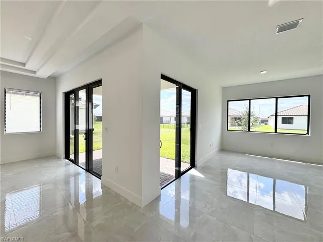 a view of an empty room with a window and chandelier