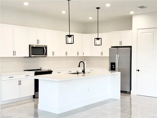 a large kitchen with stainless steel appliances kitchen island granite countertop a sink a stove and a refrigerator