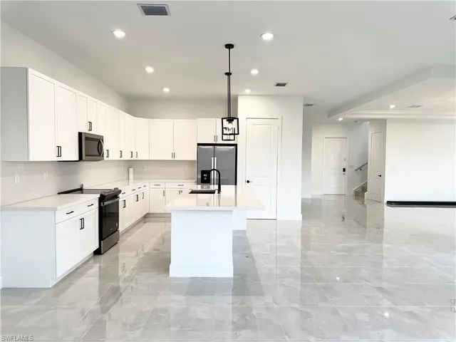 a view of kitchen with kitchen island white cabinets and refrigerator