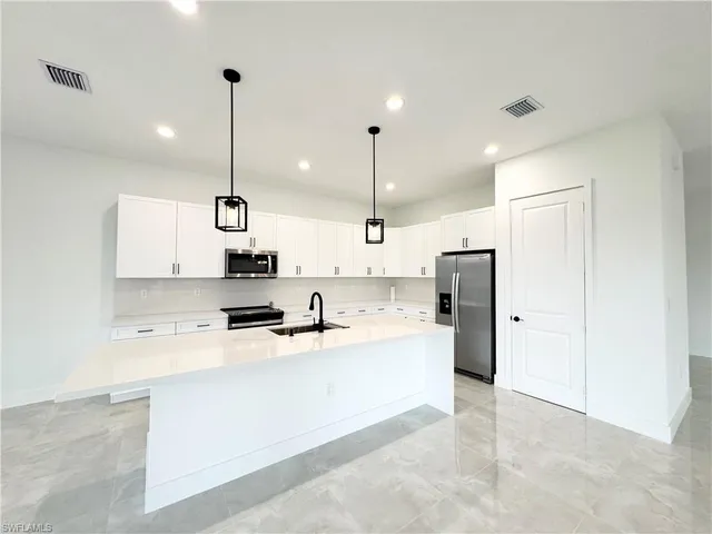 a large kitchen with stainless steel appliances kitchen island a stove a refrigerator a sink dishwasher and a oven with cabinets