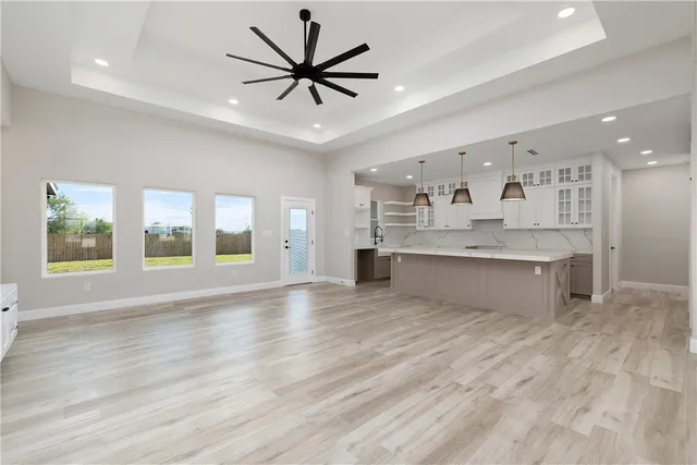 a large kitchen with stainless steel appliances granite countertop a large counter top a chandelier and a view of living room