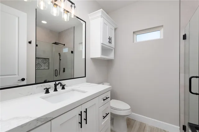 a bathroom with a sink a toilet a mirror and shower