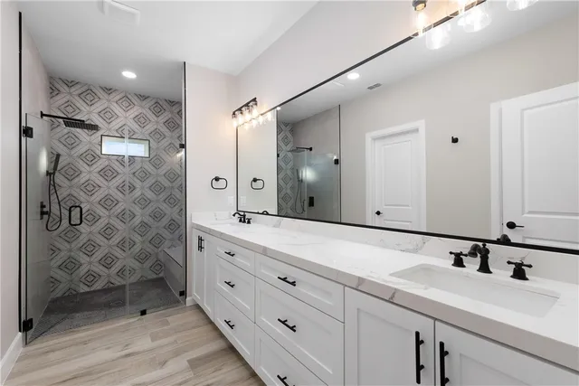 a bathroom with a double vanity sink mirror and shower