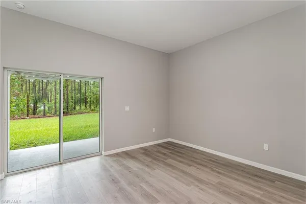 a view of an empty room with wooden floor and windows