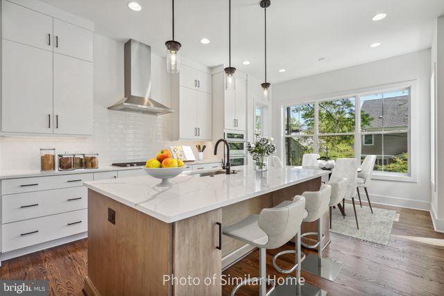 a kitchen with stainless steel appliances kitchen island granite countertop a table chairs in it and wooden floors